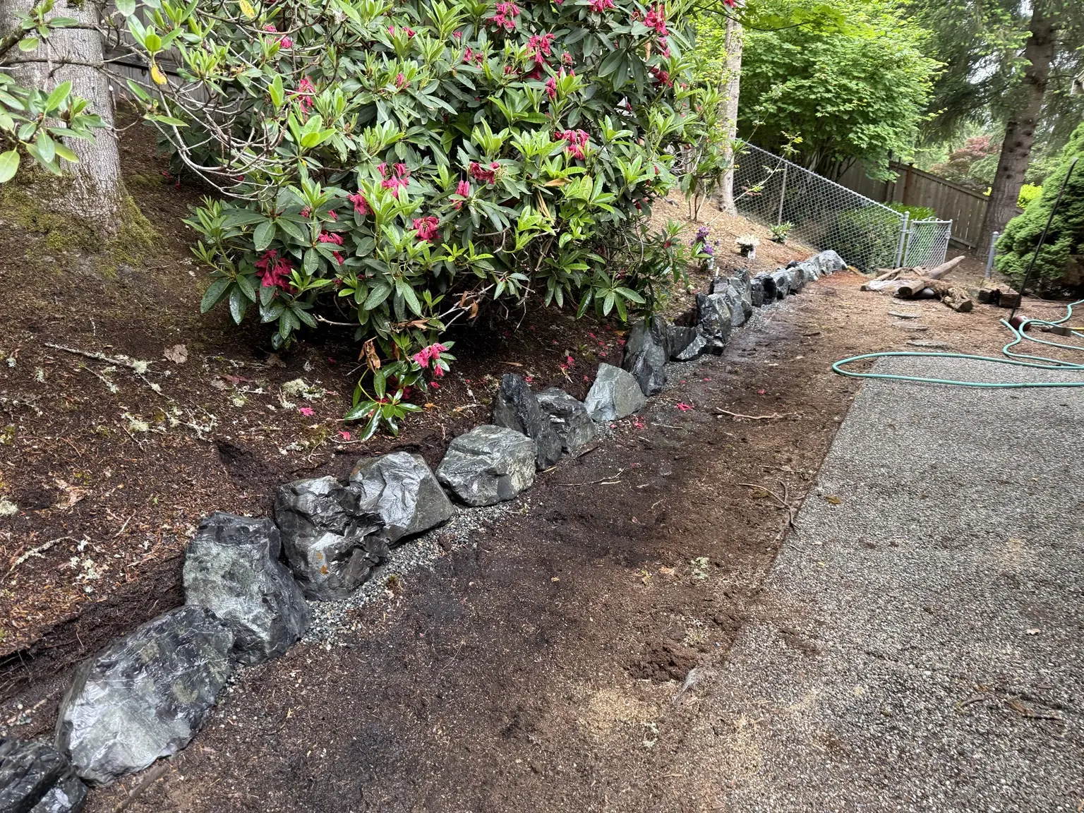 Natural rock edging installed along the planted hillside beside the entrance path
