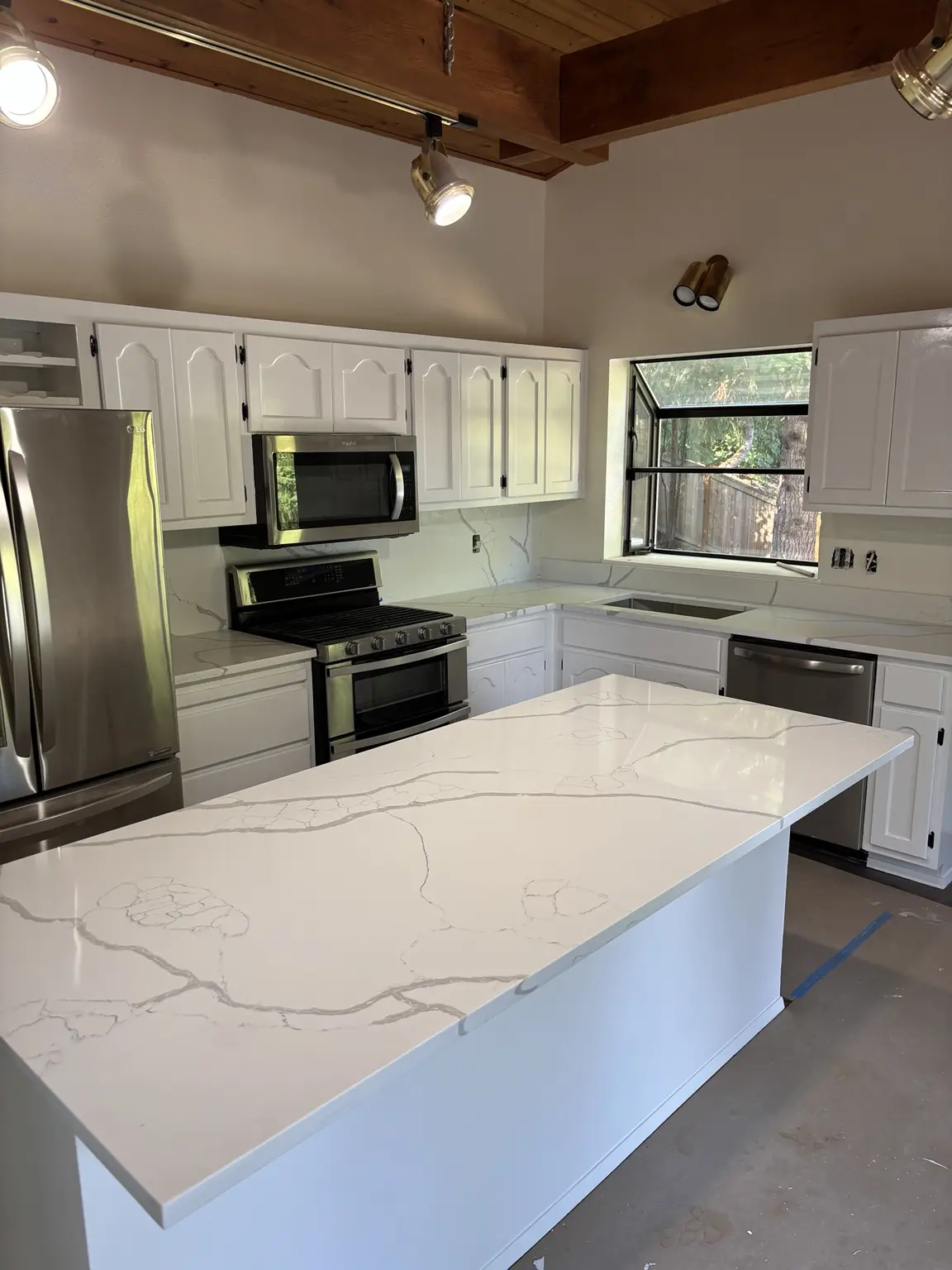 Kitchen remodel in progress with cabinets painted white and new countertops installed