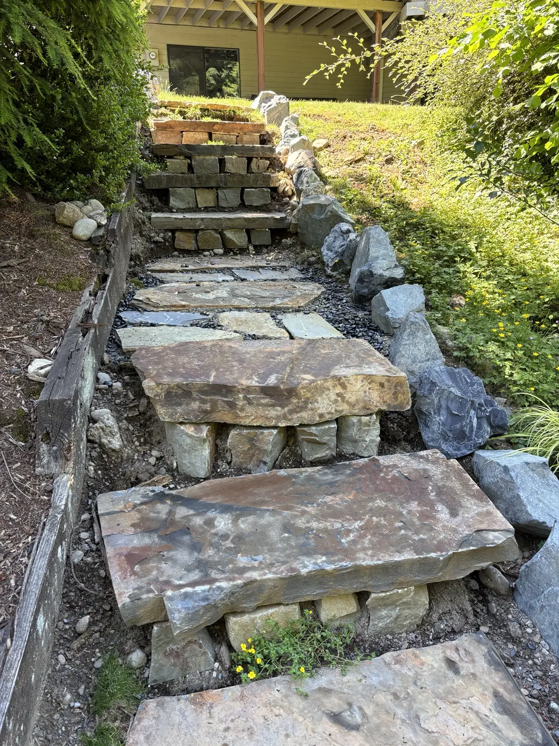 Completed natural stone stairway rising through the landscaped hillside